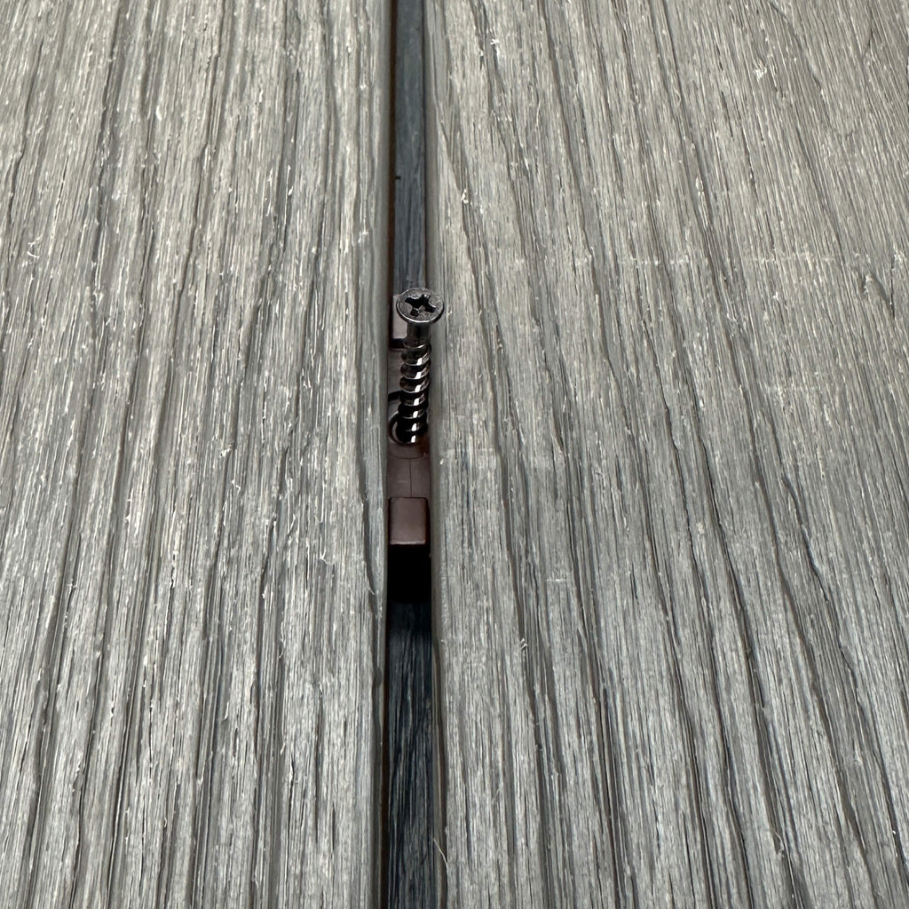 A Brown Decking Clip & Screw in situ on a decking patio background.