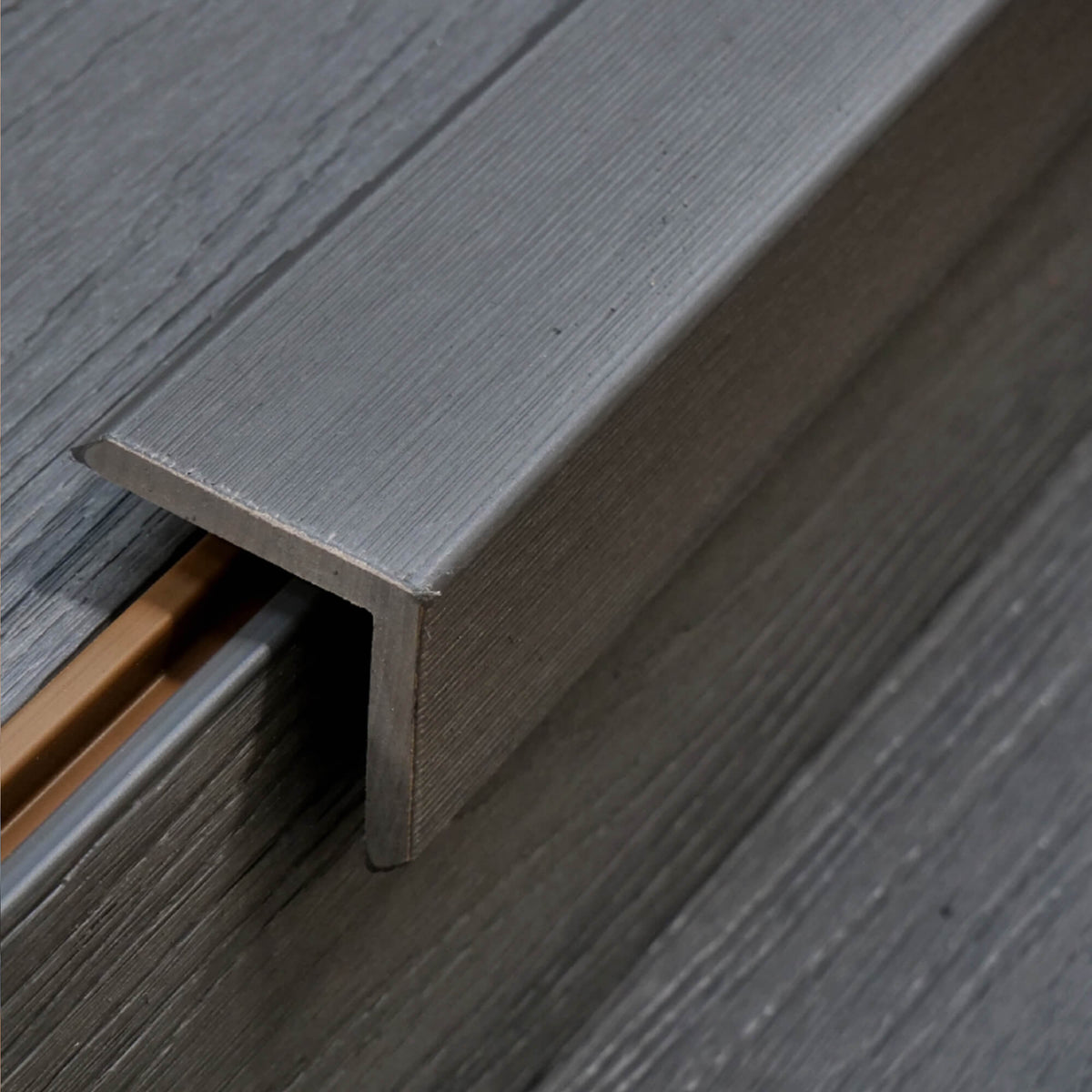 An Dark Grey Co-Extruded Composite Cover Strip in situ on decking on a patio.