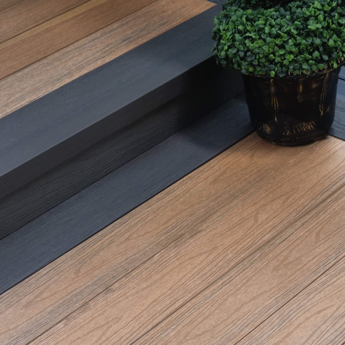 Co-Extruded Teak/Dark Grey Composite Decking in situ in a patio setting.